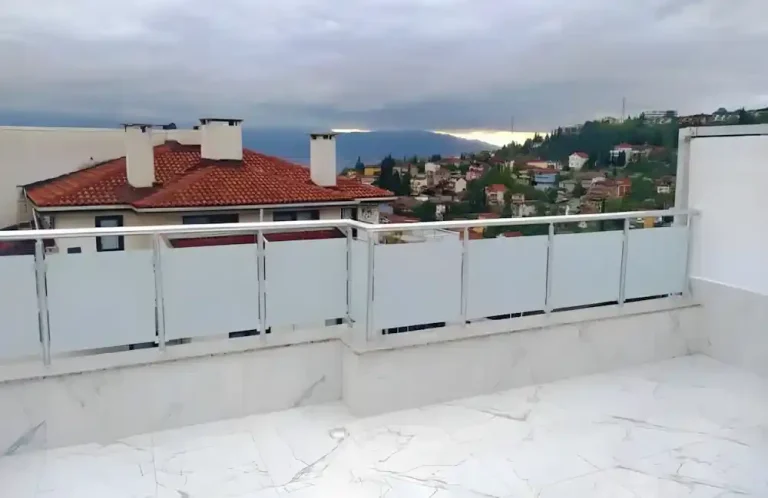 Kocaeli İzmit Akçakent 2. Etap Konutları'nda, Kocaeli PEN tarafından geniş bir terasa montajı yapılmış, şehir manzaralı, buzlu (opak) lamine camlı, modern alüminyum lamine cam küpeşte sistemi.
