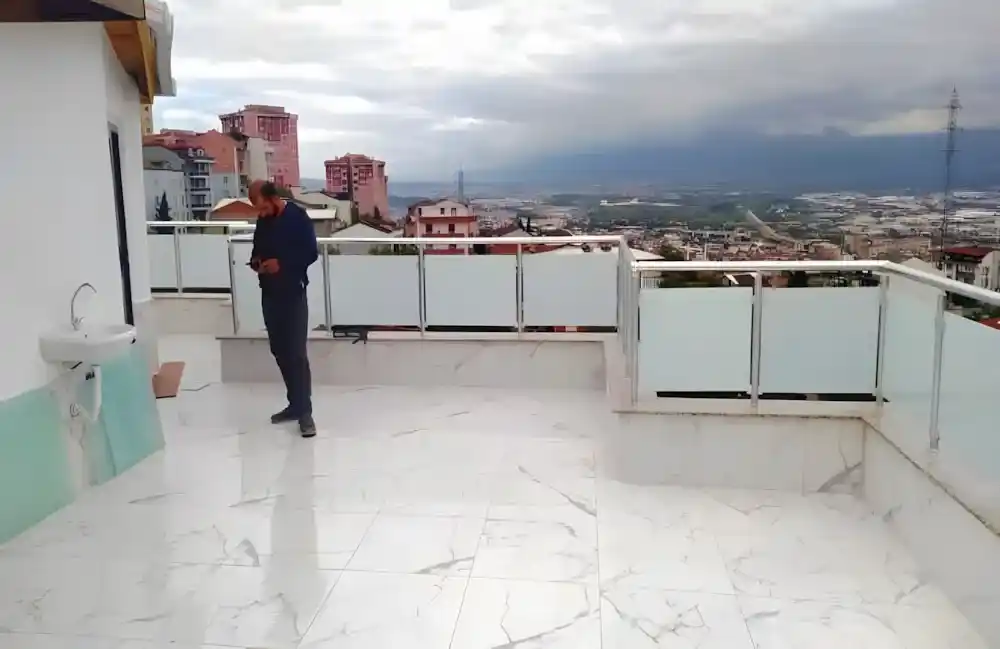 Kocaeli İzmit Akçakent 2. Etap Konutları'nda, Kocaeli PEN tarafından geniş bir terasa montajı yapılmış, şehir manzaralı, buzlu (opak) lamine camlı, modern alüminyum lamine cam küpeşte sistemi.