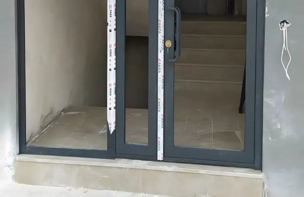 Kocaeli PEN tarafından montajı yapılmış, antrasit renkli, füme camlı, modern ve çift kanatlı kartepe alüminyum kapı apartman giriş kapısı.