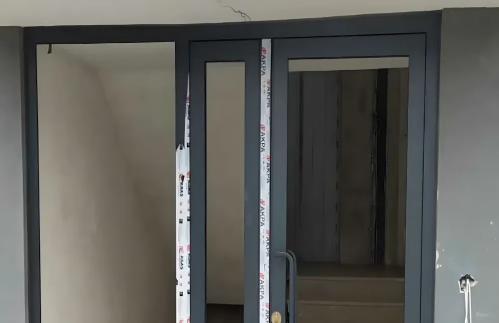 Kocaeli PEN tarafından montajı yapılmış, antrasit renkli, füme camlı, modern ve çift kanatlı kartepe alüminyum kapı apartman giriş kapısı.