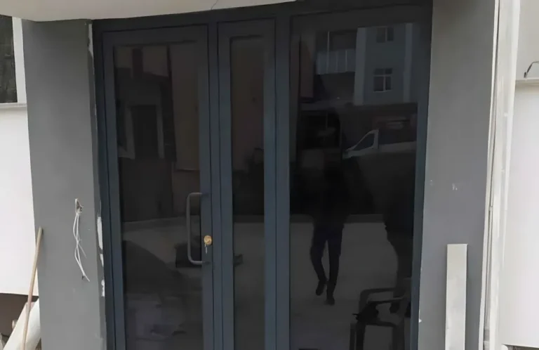 Kocaeli PEN tarafından montajı yapılmış, antrasit renkli, füme camlı, modern ve çift kanatlı kartepe alüminyum kapı apartman giriş kapısı.
