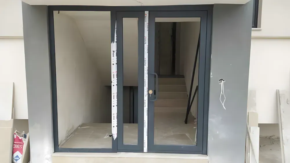 Kocaeli PEN tarafından montajı yapılmış, antrasit renkli, füme camlı, modern ve çift kanatlı kartepe alüminyum kapı apartman giriş kapısı.