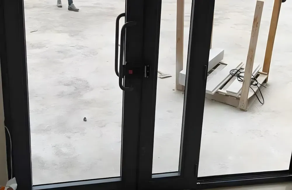 Kocaeli PEN tarafından montajı yapılmış, antrasit renkli, füme camlı, modern ve çift kanatlı kartepe alüminyum kapı apartman giriş kapısı.