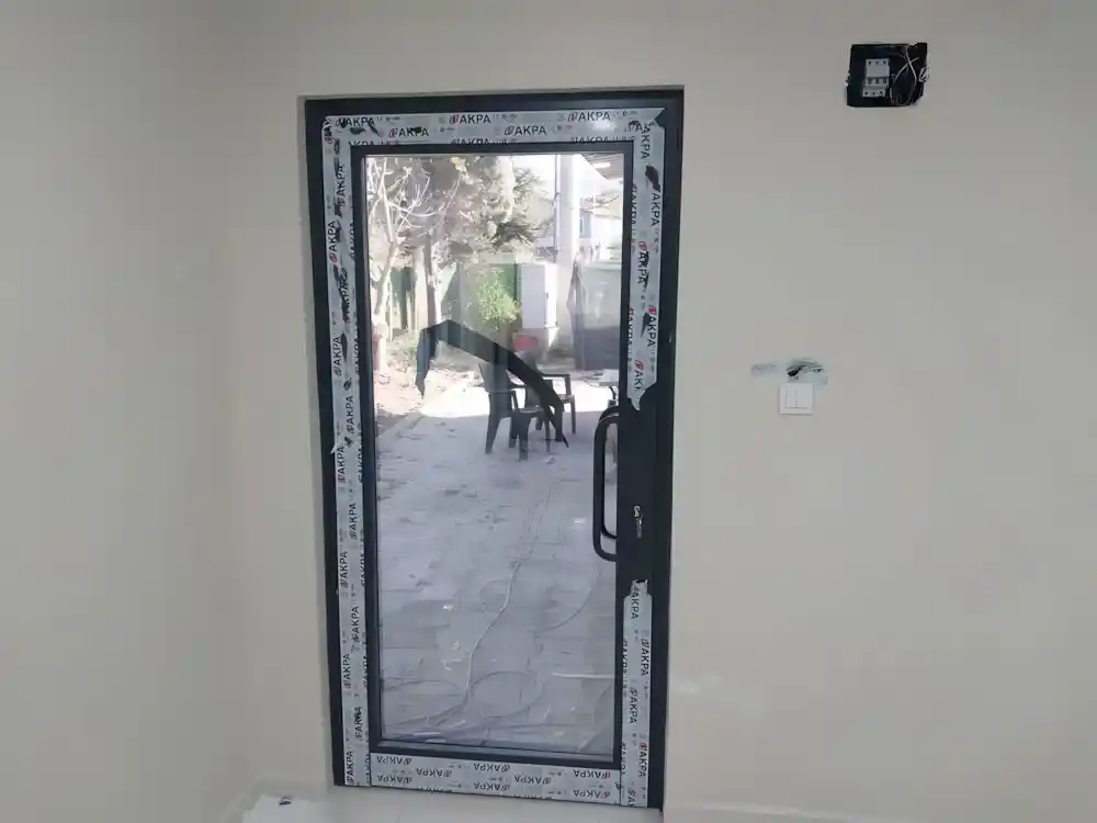 Suadiye Alüminyum Kapı Kocaeli PEN tarafından AKPA alüminyum profilleri kullanılarak montajı yeni tamamlanmış, antrasit renkli, çift kanatlı, modern bir alüminyum kapı.