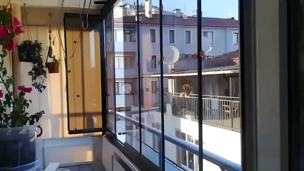 Kocaeli İzmit Merkez Cam Balkon. Kocaeli PEN tarafından montajı yapılmış, şeffaf temperli camlı, antrasit profilli, modern katlanır cam balkon.